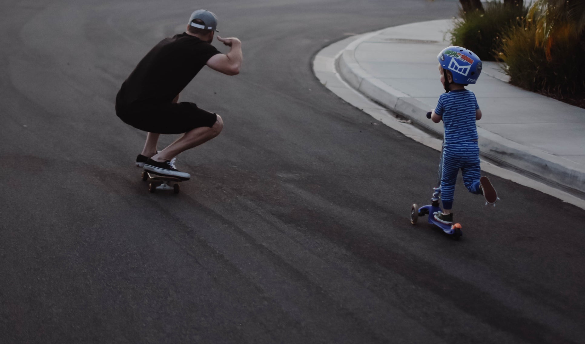 A father wearing a melin hat, and son riding a skateboard