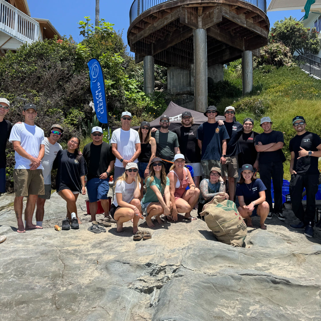 Group of melin employees x Tidy Seas posing for a photo on a rocky beach  or a beach cleanup 