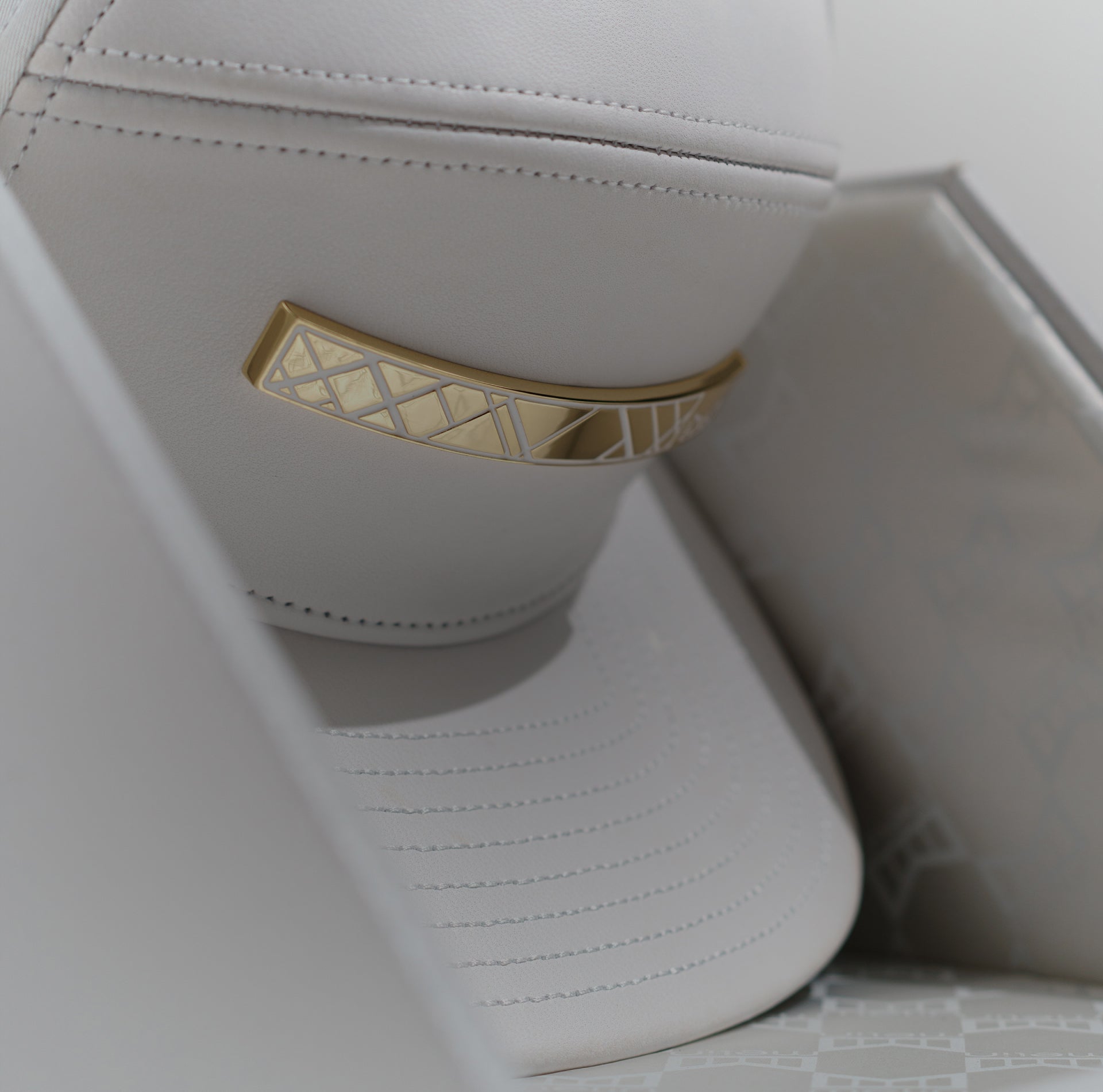 Close-up of a white leather hat with a gold accent on a light gray background