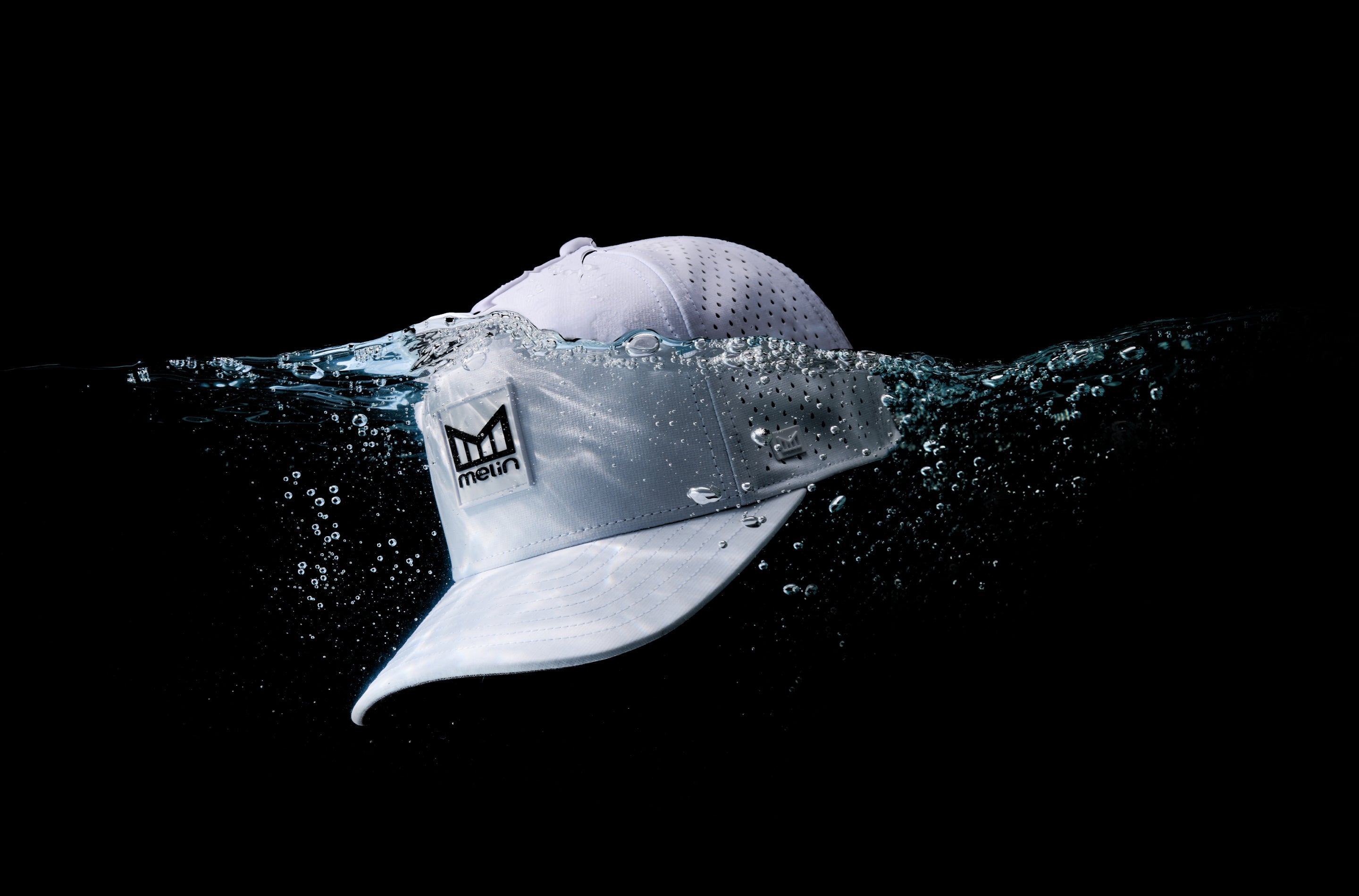 White cap with a logo submerged in water on a black background