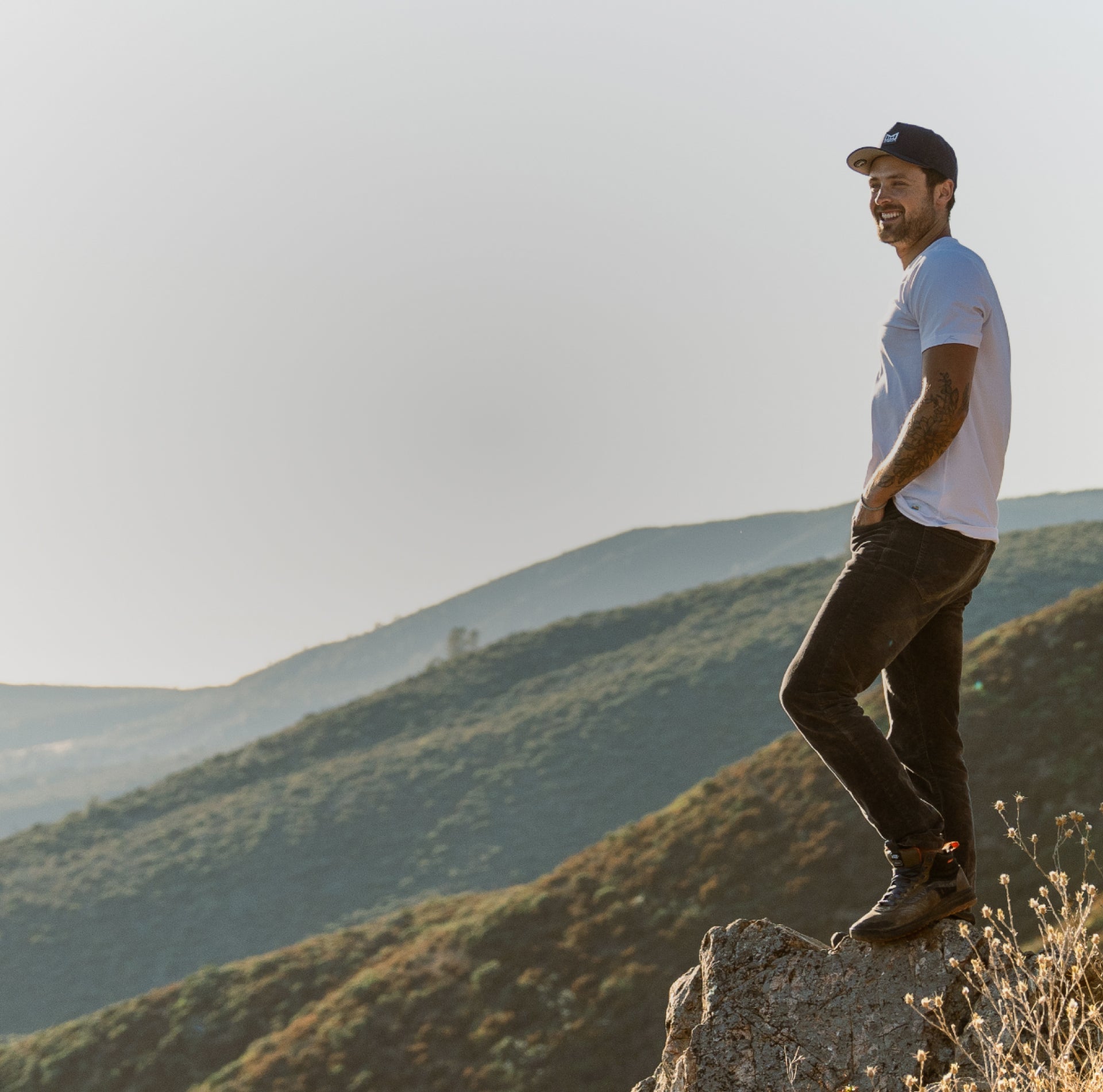 Dylan Efront standing on a rock with a scenic mountain landscape in the background