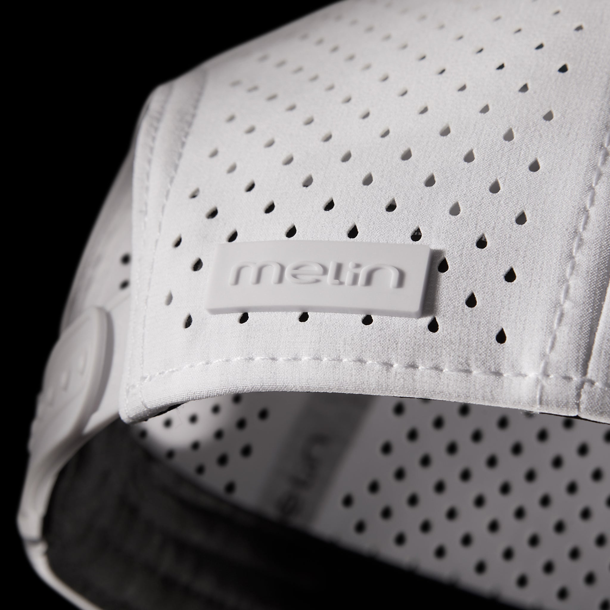 The back, side view of the melin Compass Hydro in White, featuring the melin branded license plate across the back right hat panel