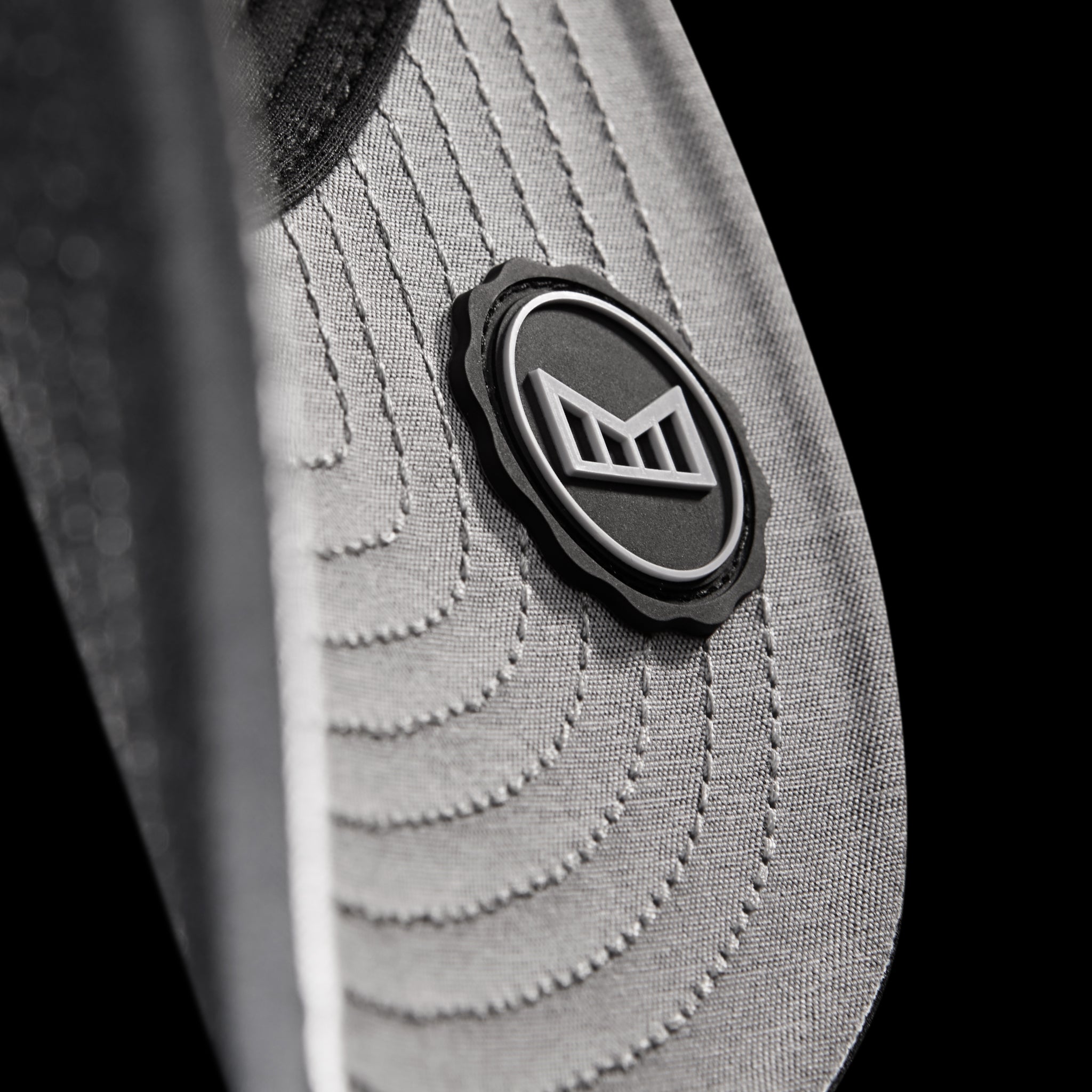 The undervisor seal of the melin Compass Hydro in Heather Charcoal, set against a black background